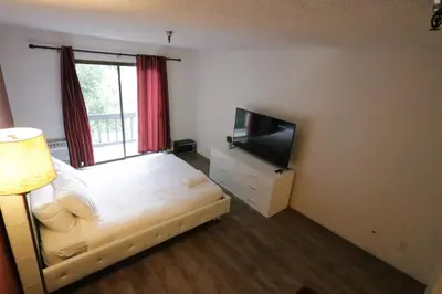 a bedroom with a bed and a flat screen tv at Cozy Beverly Hills Hotel Style apartment in Los Angeles