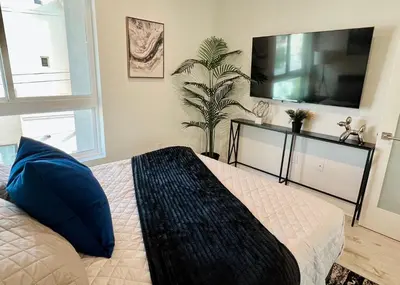 a bedroom with a bed with blue pillows and a tv at Cozy Century City 2 Br Sleeps 6 with Parking 505 in Los Angeles