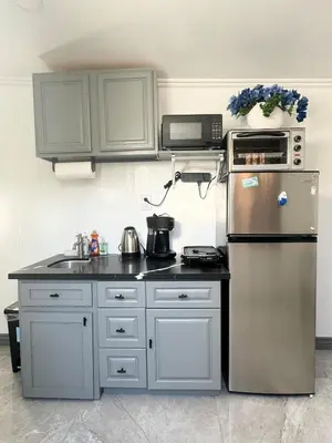 a kitchen with white cabinets and a stainless steel refrigerator at Asian Food Gallery mini back room in San Gabriel