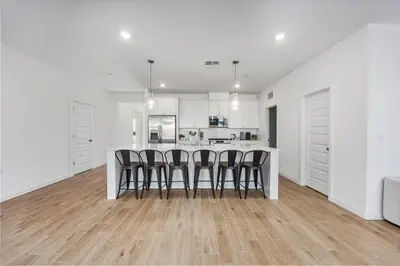 a white kitchen with a bar with stools at Serenity House- Newly Built, Peaceful Stay in Bakersfield