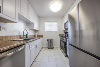 a kitchen with white cabinets and a stainless steel refrigerator at Spacious 2-Bedroom Duplex in Beverly Hills Residential Area in Los Angeles