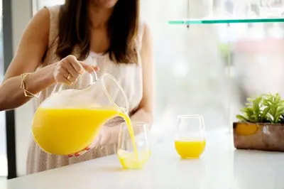 a woman pouring an orange juice into a glass at Hyatt House Cypress / Anaheim in Cypress