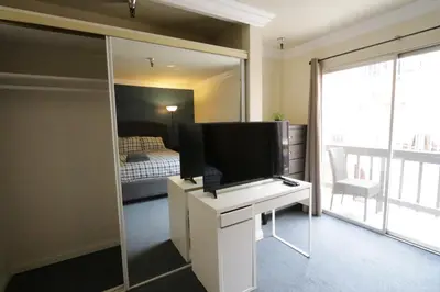 a bedroom with a tv on a desk with a mirror at Beverly Hills Queen Bed Studio in Los Angeles