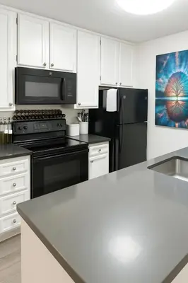 a kitchen with white cabinets and black appliances at Hollywood Hills Haven - Resort Living Near Universal Studios & Warner Bros in Los Angeles