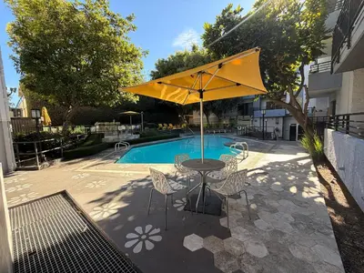 a table with a yellow umbrella next to a pool at Serene Stay with Pool Access & Balcony in Los Angeles