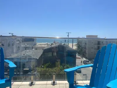 a view of a city from a balcony with blue chairs at Beach Sweet condo home in Los Angeles