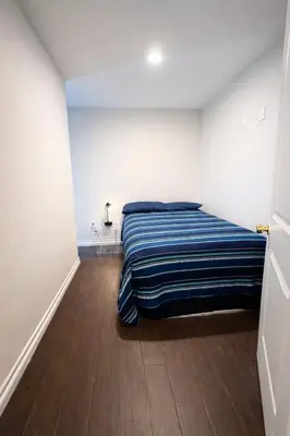 a bedroom with a bed with a blue striped blanket at Vernon Homes For The Soul in Los Angeles