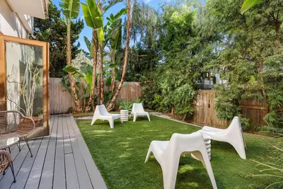a backyard with white chairs and a lawn at Vibrant SoCal Venice Beach Retreat in Los Angeles