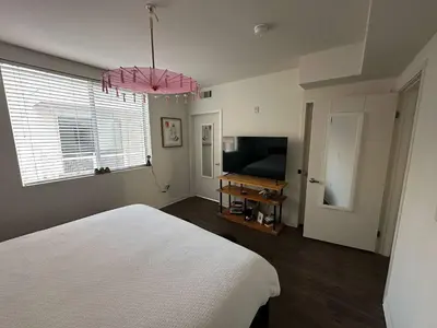 a bedroom with a white bed and a television at Walk to Beach & Promenade Cozy Santa Monica Condo in Los Angeles