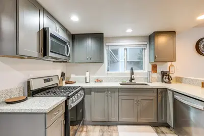 a kitchen with stainless steel appliances and gray cabinets at 1 Mi to Lake Gregory! Updated Family Home with Deck in Crestline