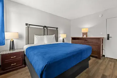 a bedroom with a large bed with a blue blanket at Studio Lodge Hotel in Hewitt