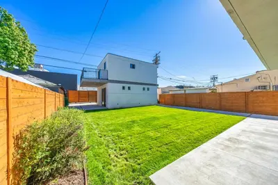 a yard with a white house and a fence at 2BR 2BA Villa in Melrose with Free Parking in Los Angeles