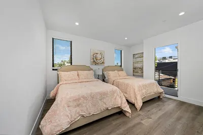 two beds in a bedroom with white walls and windows at 7 BR double house with parking and a backyard in LA in Los Angeles