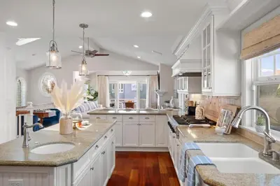 a kitchen with white cabinets and sinks and a window at 4br Beach House Steps from Beach with AC Parking BBQ in Hermosa Beach