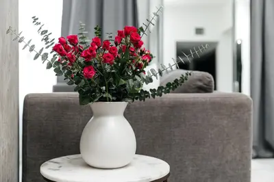 a white vase filled with red roses on a table at City Sanctuary - Urban Hideaway in Los Angeles