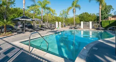 a swimming pool at a resort with palm trees at Charming 3BR Apartment | Near Disney + Arcade in Placentia
