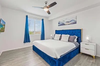 a bedroom with a blue bed and a window at Charming 3BR Apartment | Near Disney + Arcade in Placentia