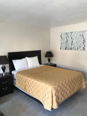 a bedroom with a large bed with two night stands and two lamps at Akua Inn & Suites - Anaheim - Fullerton in Anaheim