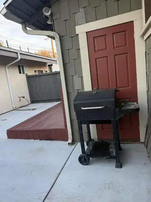 a grill sitting outside of a house with a red door at Family gateway in the heart of Los Angeles 2bedroom 2bath backyard in Los Angeles