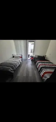 two beds in a room with a window at Shared but isolated room in a shared soace in Los Angeles