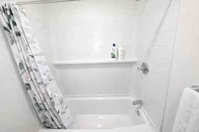 a white bathroom with a tub and a shower at Brand new private Home with Yard free parking, near Ontario airport in Ontario