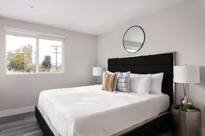 a white bedroom with a large bed with a mirror at Relax in Spacious 4BR Home Sleeps 8 with Parking in North Hollywood