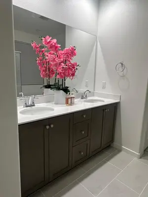 a bathroom with a sink and a mirror and pink flowers at Ali's home in Fontana