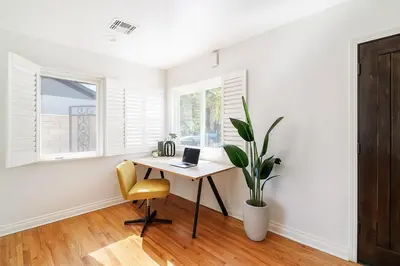 a white room with a desk with a laptop and a plant at Modern Tarzana Poolside Retreat in Tarzana