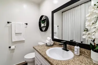 a bathroom with a sink and a toilet and a mirror at Modern Tarzana Poolside Retreat in Tarzana