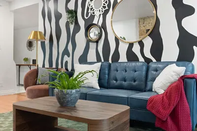 a living room with a blue couch and a mirror at Stylish Getaway with Hot Tub in Northridge Hospital Heliport