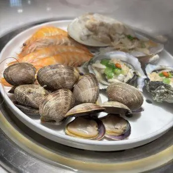 a plate of clams and oysters on a table at YouPeng Seafood and GO Believe