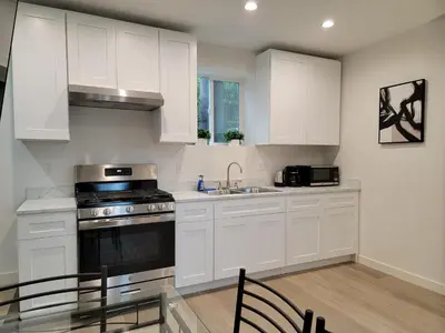 a kitchen with white cabinets and a sink and a stove at Spacious 2-Bedroom, One and a Half Bath Home in Pico-Robertson Near Beverly Hills and Cedars-Sinai in Los Angeles