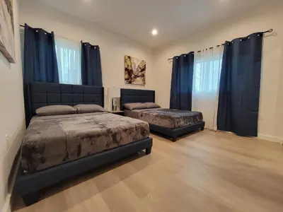 two beds in a bedroom with blue curtains at Spacious 2-Bedroom, One and a Half Bath Home in Pico-Robertson Near Beverly Hills and Cedars-Sinai in Los Angeles
