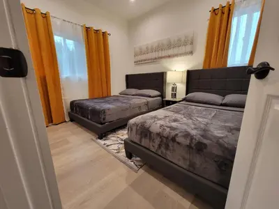 a bedroom with two beds and orange curtains at Spacious 2-Bedroom, One and a Half Bath Home in Pico-Robertson Near Beverly Hills and Cedars-Sinai in Los Angeles