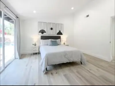 a white bedroom with a bed and a large window at stunning Poolside villa