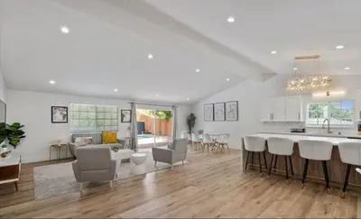 a kitchen and living room with white walls and wood floors at stunning Poolside villa