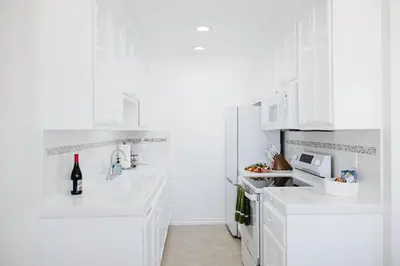 a white kitchen with white cabinets and a bottle of wine at The Sovereign in Los Angeles
