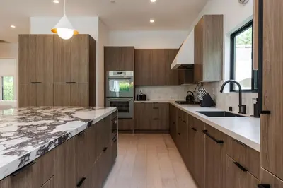 a kitchen with wooden cabinets and marble counter tops at Modern Poolside Paradise in Sherman Oaks