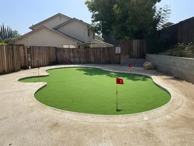 a putting green with a red flag in a driveway at 5 bedroom home 2 miles from Loma Linda Medical in Loma Linda