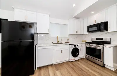 a kitchen with white cabinets and a black refrigerator at Stellar Sherman Oaks One Bedroom close to Universal Studios in Burbank