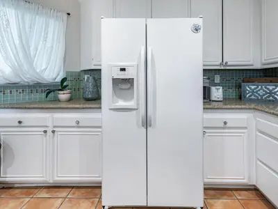 a white refrigerator in a kitchen with white cabinets at Apartment Meerblick Eigentumswohnung gegenüber dem Strand by Interhome in Port Hueneme
