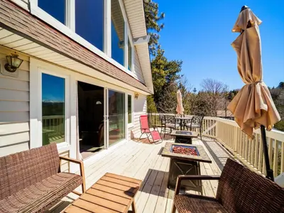 a deck with chairs and a table and an umbrella at Holiday Home Haus mit Seeblick - Atemberaubende Aussicht - Haustierfreundlich by Interhome in Lake Arrowhead