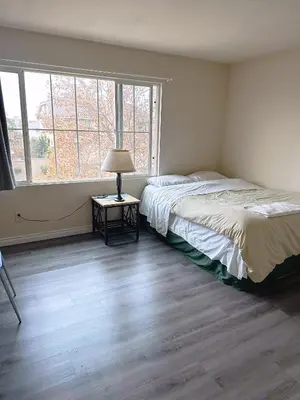 a bedroom with a bed and a lamp on a table at Big bedroom shared bathroom in Fontana