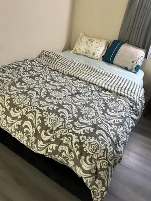 a bed with a black and white comforter on it at Big bedroom shared bathroom in Fontana