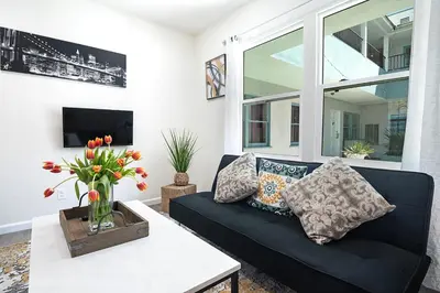 a living room with a black couch and a vase of flowers at Cozy Studio Suite Near Beverly Hills in Los Angeles