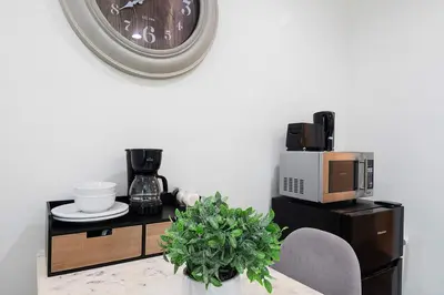 a clock on a wall above a table with a microwave at Cozy Studio Suite Near Beverly Hills in Los Angeles