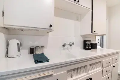 a white kitchen with a sink and a coffee maker at Bright Second-Floor Studio Near Beverly Hills in Los Angeles