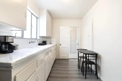 a white kitchen with a counter and stools in it at Comfortable 1B 2beds Retreat Near Beverly Hills in Los Angeles