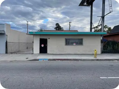 a white building with a door on a street at Hidden Gem in San Bernardino