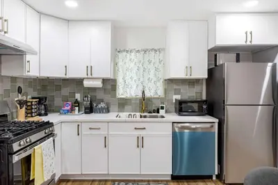 a kitchen with white cabinets and a stainless steel refrigerator at Family Retreat Near Disneyland & Downtown LA 4BR in Los Angeles